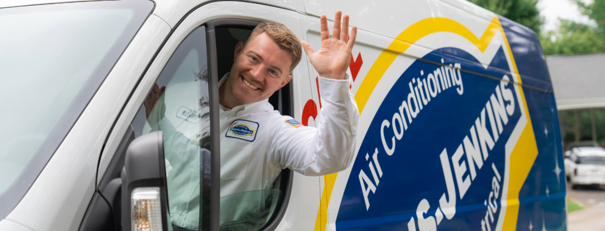 A person in a uniform waves from the driver's seat of an air conditioning service van with "Jenkins" written on the side.
