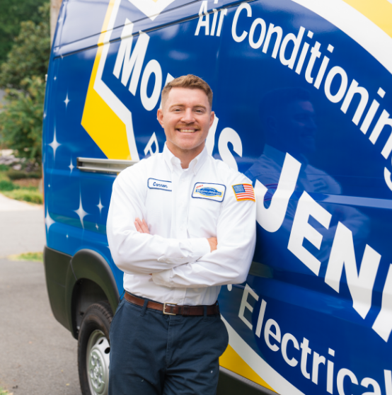 A person in a uniform, labeled with "Cameron," stands smiling with arms crossed in front of a blue air conditioning service van.